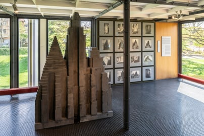Innenausstellung mit abstrakter Skulptur und Fotos an der Wand.
