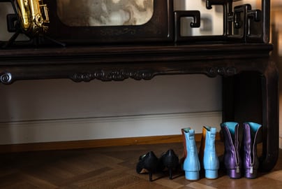 Stiefel und Schuhe unter Holztisch mit Saxophon obenauf.