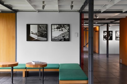 Museumsausstellung mit Sitzbank und Schwarz-Weiss-Fotografien an der Wand.