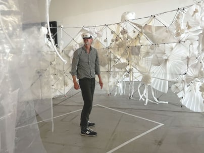 Person mit VR-Brille vor Kunstinstallation aus Papierstrukturen.