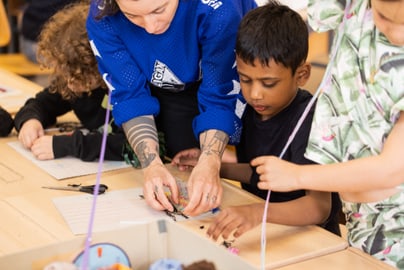 Kursleiterin hilft Kindern bei Bastelaktivitäten.