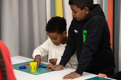Zwei Kinder beim Kneten am Tisch im Klassenzimmer.