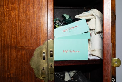 Offener Holzschrank mit Schuhkartons und Kleidung.