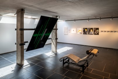 Innenraum mit Liegestuhl und Kunstwerken an den Wänden.