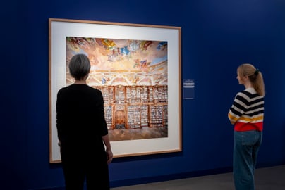 Zwei Personen betrachten ein Gemälde in einem Museum.