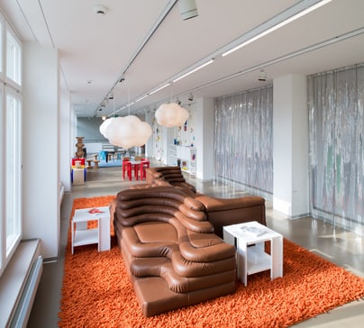 Moderne Lounge mit braunem Sofa und orangefarbenem Teppich.