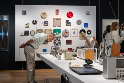 Mann betrachtet alte Audiogeräte im Museum.