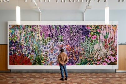 Person betrachtet grosses, buntes Blumenwandbild im Innenraum.