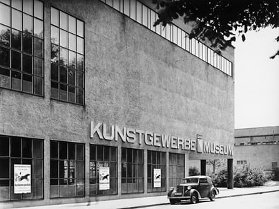 Schwarzweiss-Foto eines Kunstgewerbemuseums mit geparktem Auto.