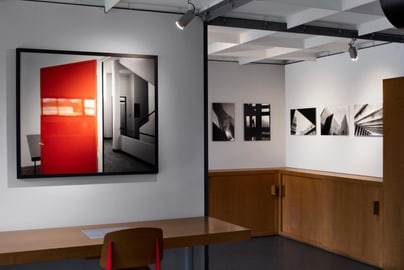 Kunstgalerie mit Fotos an der Wand, rotes Bild im Vordergrund.