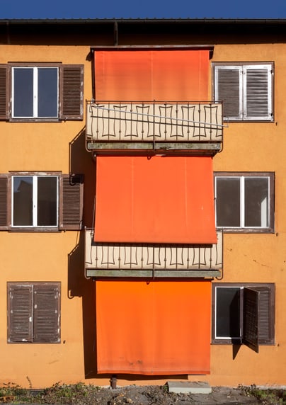 Gelbes Gebäude mit orangefarbenen Markisen und Fenstern.