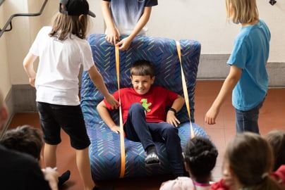 Kinder spielen auf einem grossen selbstgebastelten Stuhl.