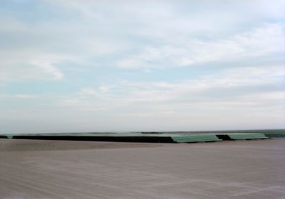 Rohre auf einem grossen, sonnigen Feld unter blauem Himmel.