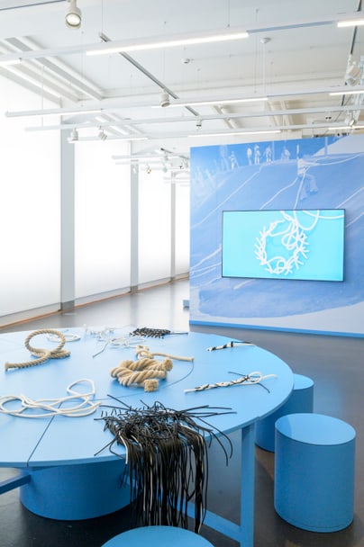 Kunstinstallation mit blauen Möbeln und Seilen in einem hellen Raum.