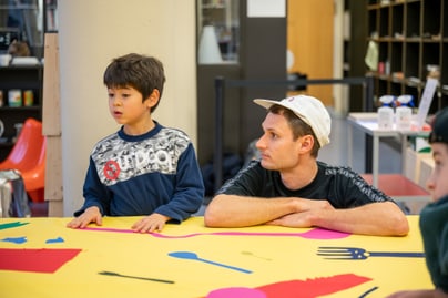 Mann und kleiner Junge an einem Tisch mit buntem Papier.