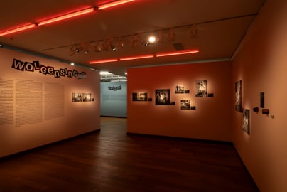 Beleuchteter Ausstellungsraum mit Fotos an den Wänden.