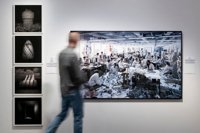 Person betrachtet Bilder in Galerie, einschliesslich grossformatigem Bürobild.