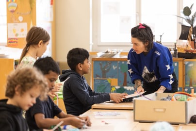 Kursleiterin hilft Kindern im bei Bastelprojekt.