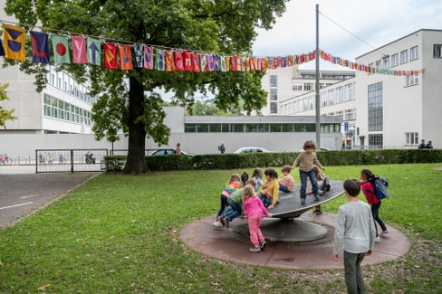 Kinder spielen auf einem Karussell im Park vor dem Museum für Gestaltung.