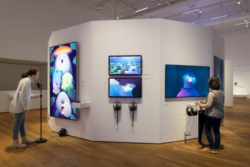 Menschen betrachten bunte digitale Kunst in einer Galerieausstellung.
