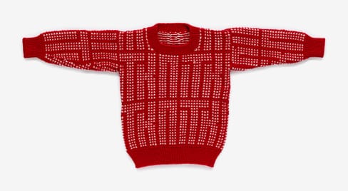 Roter Pullover mit weissem Muster ausgebreitet auf weissem Hintergrund.