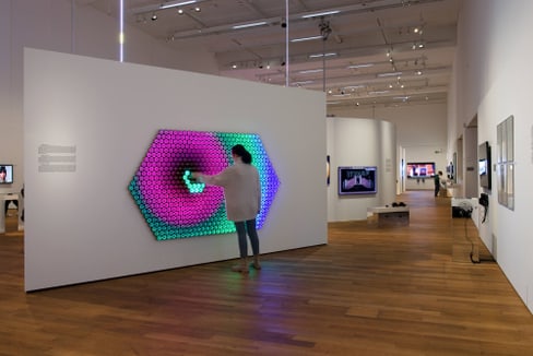 Person interagiert mit interaktivem Kunstwerk im Museum.