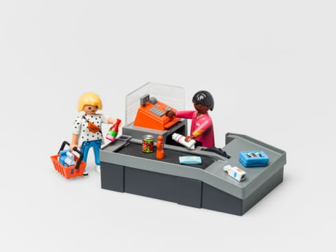 Playmobil-Figuren an der Supermarktkasse mit Einkäufen.
