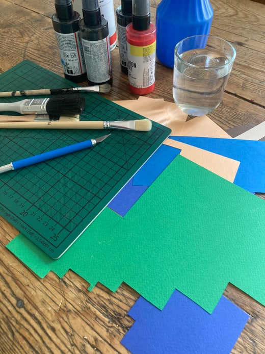 Kunstbedarf auf einem Tisch, einschliesslich Malutensilien und Papier.