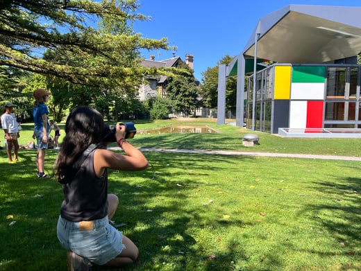 Frau fotografiert modernes Gebäude im Park bei Sonnenschein.