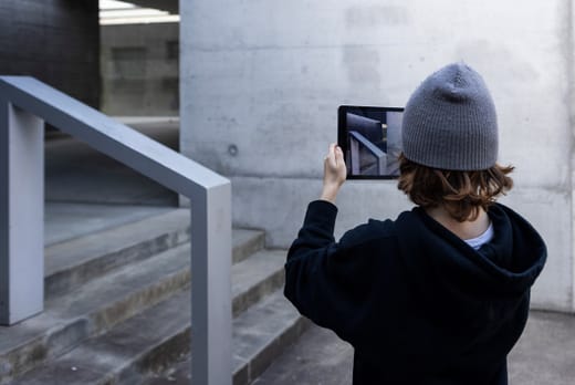 Person mit grauer Mütze macht Foto mit Tablet von Treppe.