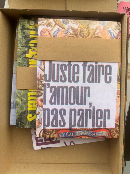 Schachtel mit Papieren, 'Juste faire l'amour, pas parler' vorne sichtbar.