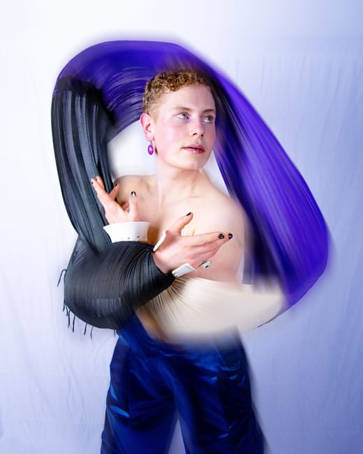 Person in künstlerischer Pose mit buntem Stoff umwickelt.