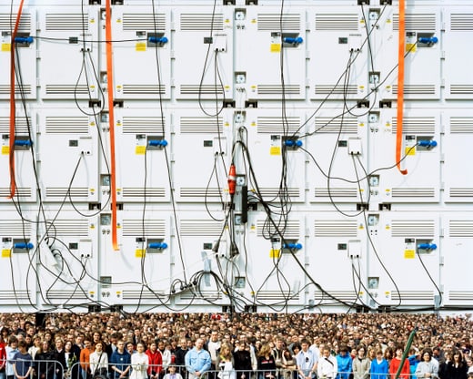 Menschenmenge vor technischer Wand mit Kabeln.