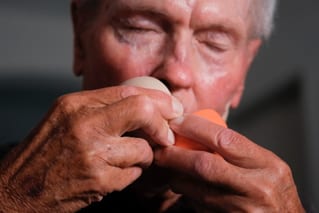 Älterer Mann hält Bälle in der Hand nah am Gesicht.