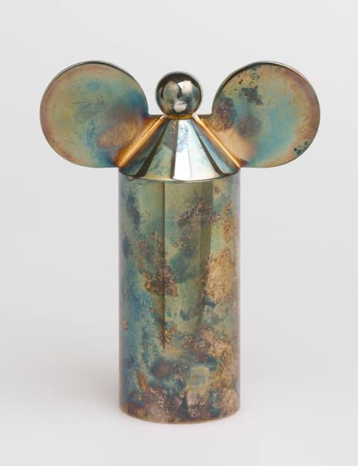 Metallic sculpture with cylindrical body and round ears.