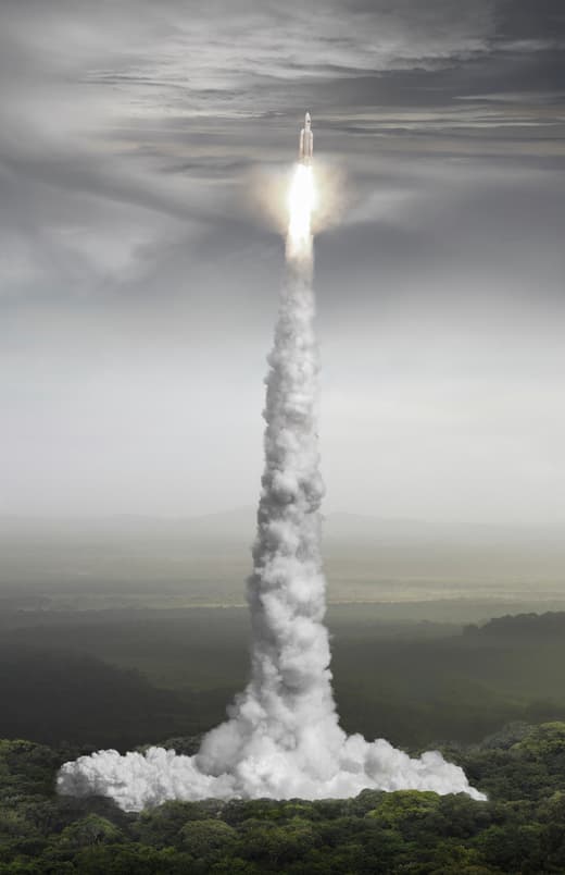 Rakete startet in den Himmel über Waldgebiet.