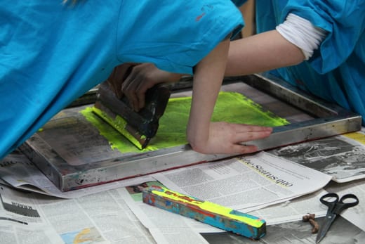 Personen beim Siebdruck auf Papier mit Farbe.