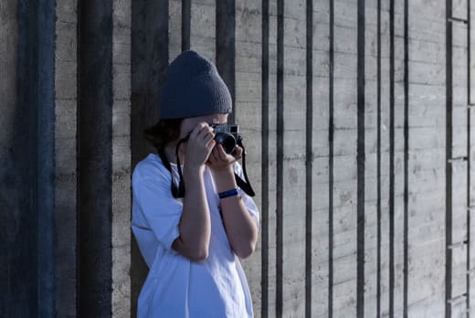 Person mit Mütze fotografiert an Betonwand.