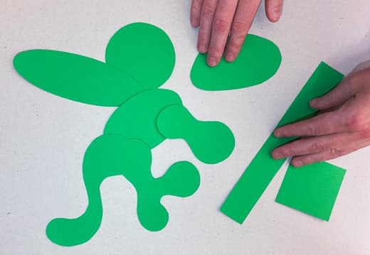 Grüne Papierformen und Hände auf weissem Hintergrund.