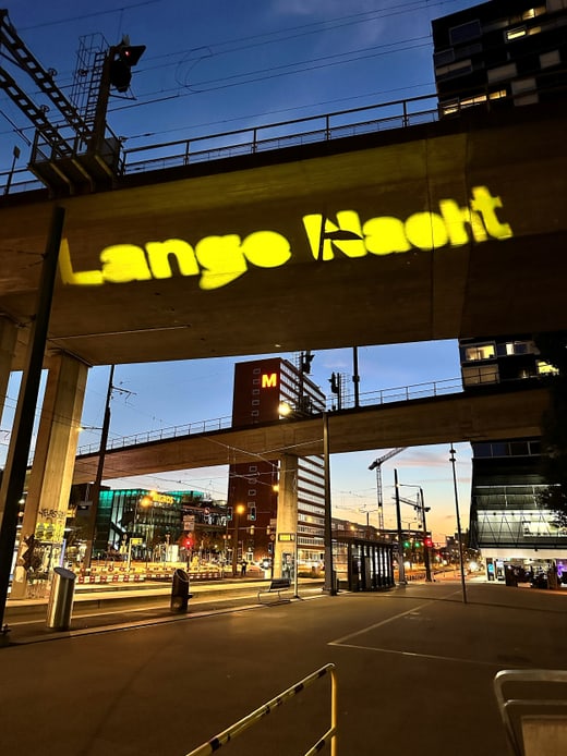 Gelbes Lichtprojektionsschild 'Lange Nacht' auf Brücke bei Nacht.