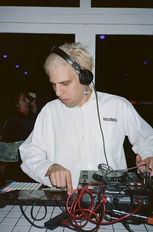 Person mit Kopfhörern spielt Musik an DJ-Pult.