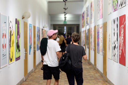 Menschen gehen durch Kunstgalerie mit Plakaten an den Wänden.
