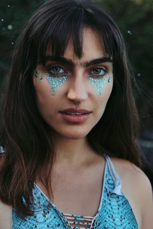 Frau mit blauem Glitzer-Make-up im Gesicht im Freien.