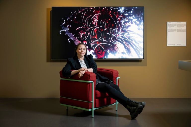 Person sitzt in rotem Sessel vor abstraktem Kunstwerk.