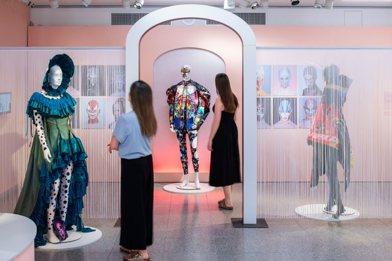 Leute betrachten ausgestellte Modekleidung in einem Museum.