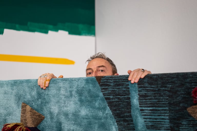Eine Person, die hinter einem bunten Teppich hervorschaut.